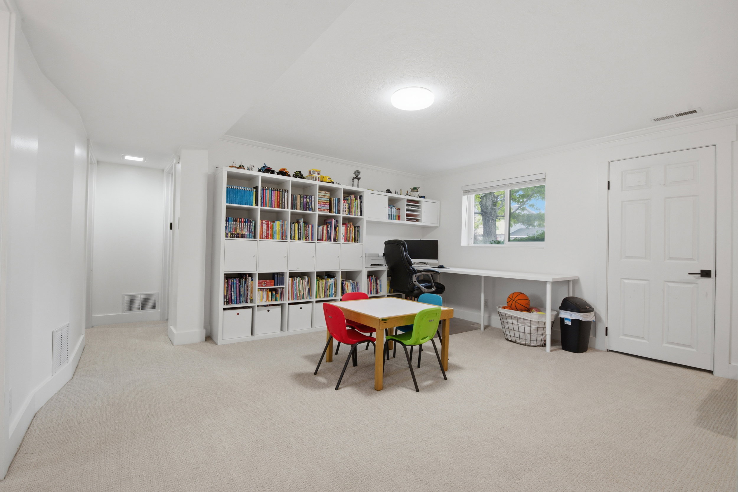 Spacious room featuring light-colored carpeting, white walls, and bright overhead lighting