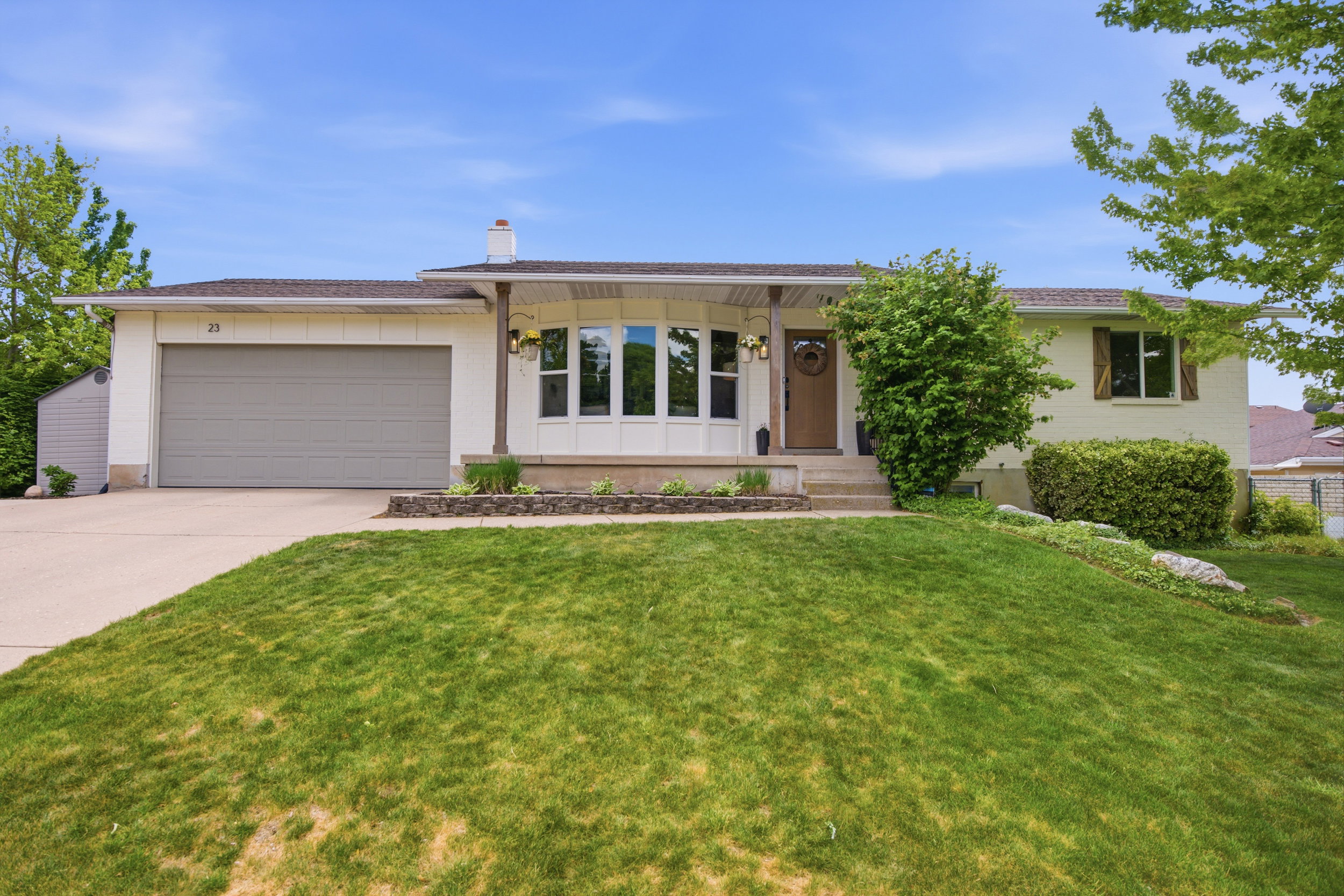 Ranch-style exterior featuring a prominent bay window, attached garage, and a concrete driveway