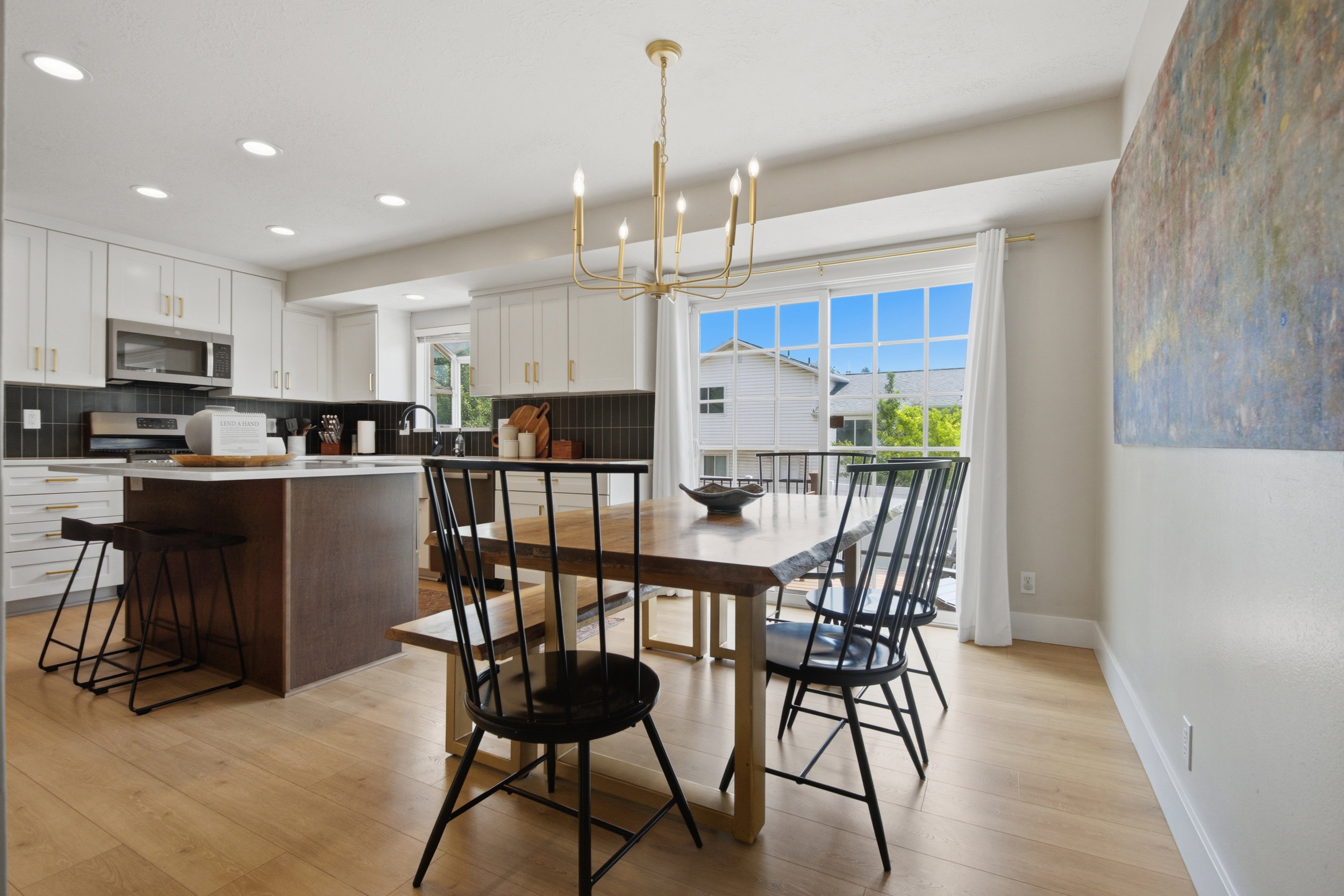 Open-concept kitchen and dining area featuring light wood-finish flooring, a contemporary gold-tone chandelier, and recessed lighting