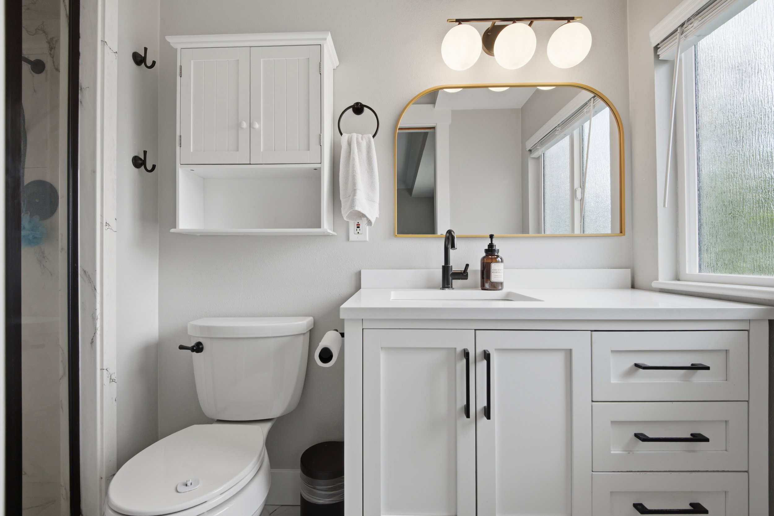 Bathroom featuring a white vanity with black hardware, a rectangular undermount sink, and a white countertop