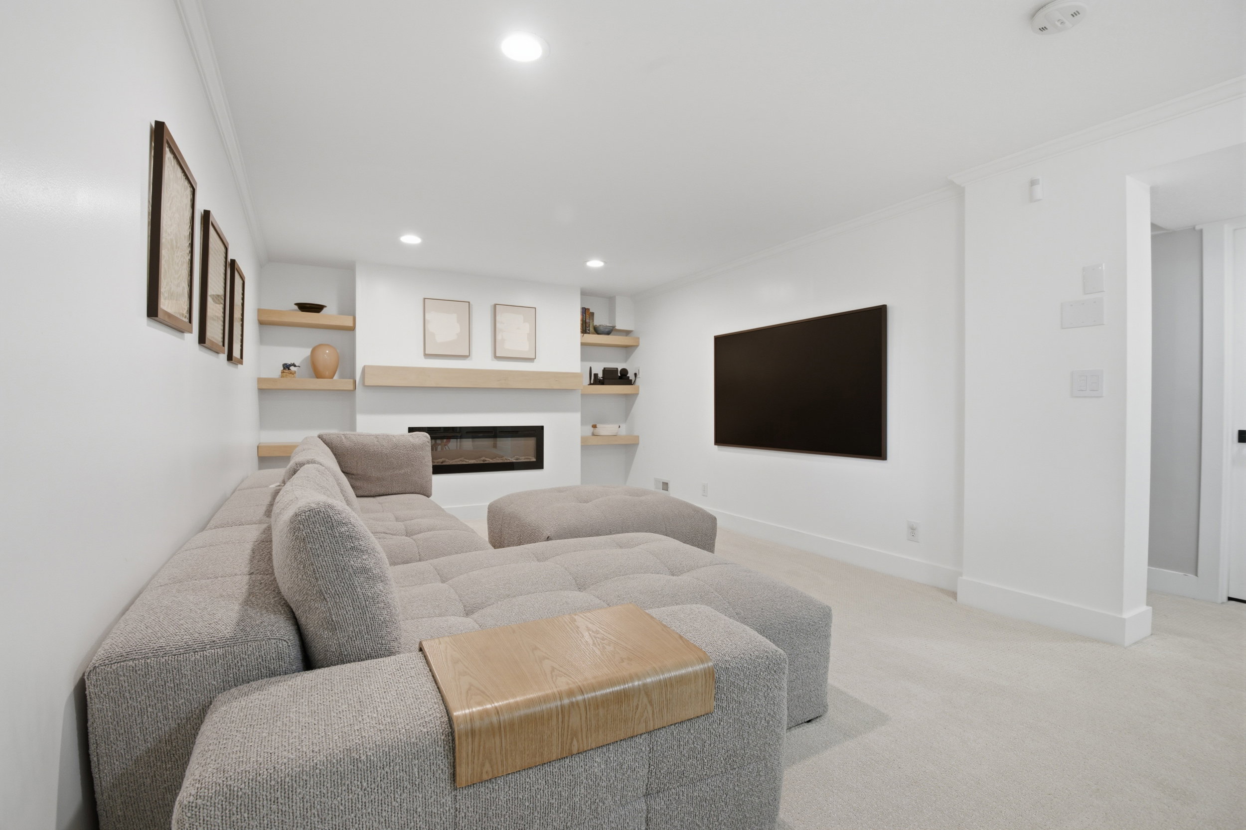 Living area featuring a linear fireplace with a wood mantle, integrated shelving, recessed lighting, and wall-to-wall carpeting