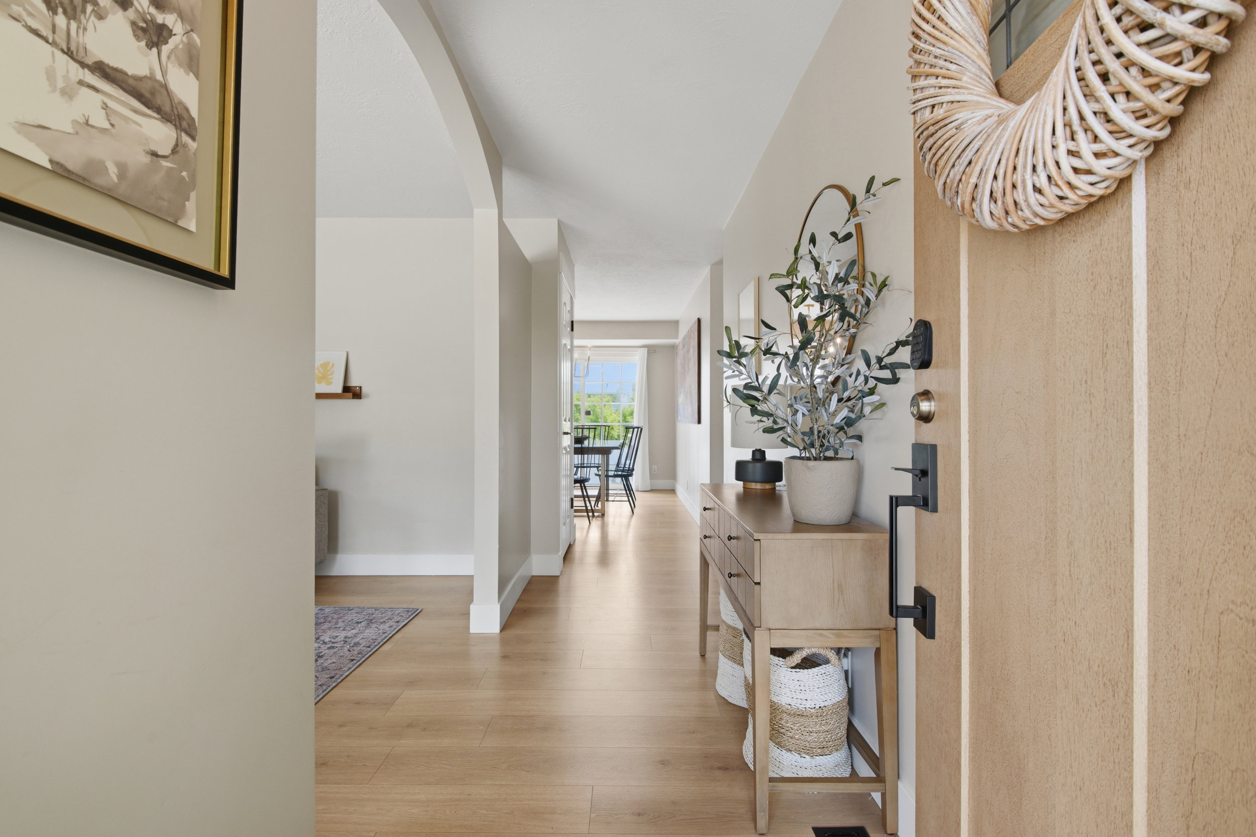 Entryway featuring a light wood-finish door with black hardware, wood-finish flooring, and light-toned walls