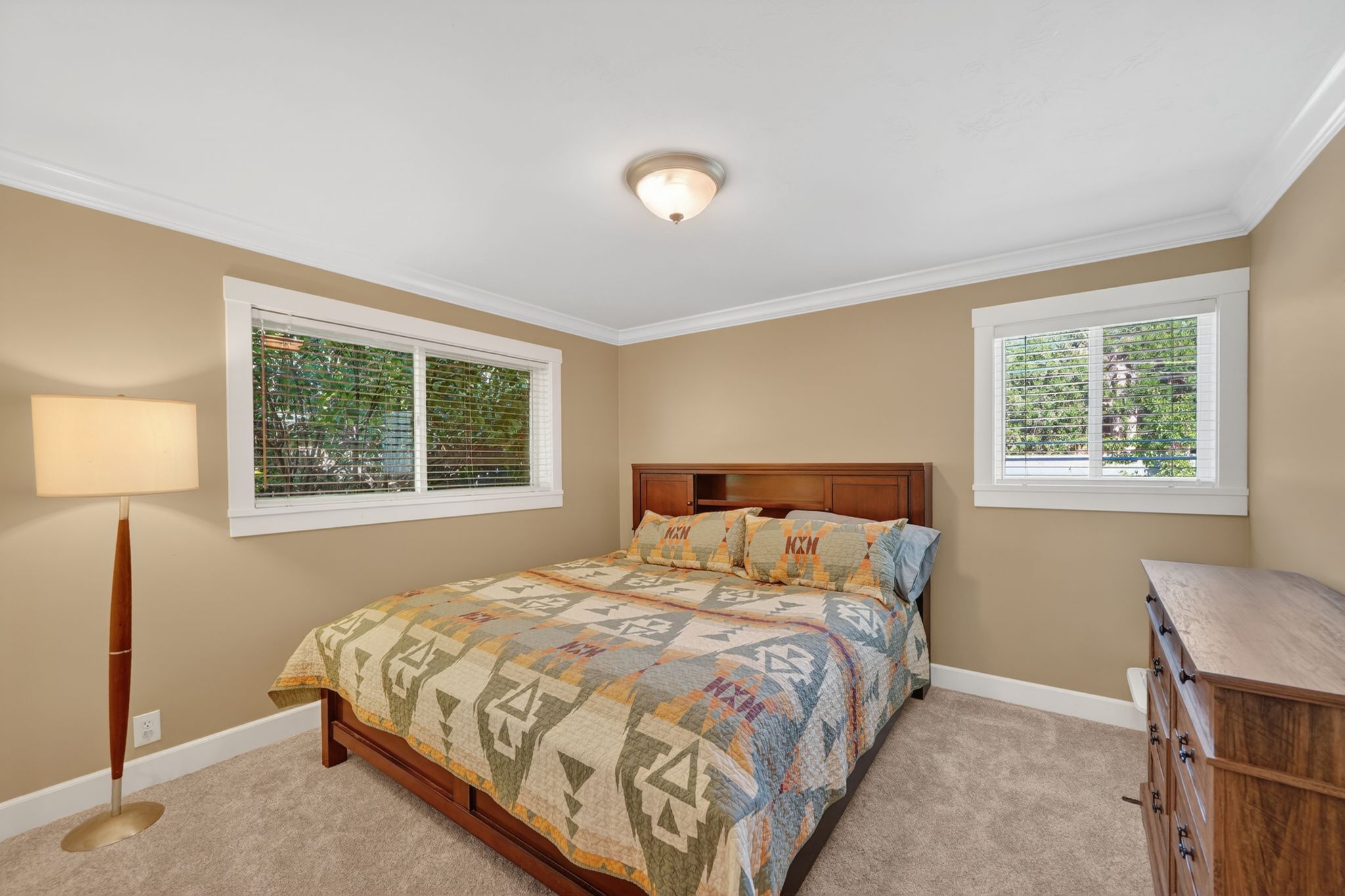 Carpeted room with crown molding, two windows with blinds, and light-toned walls