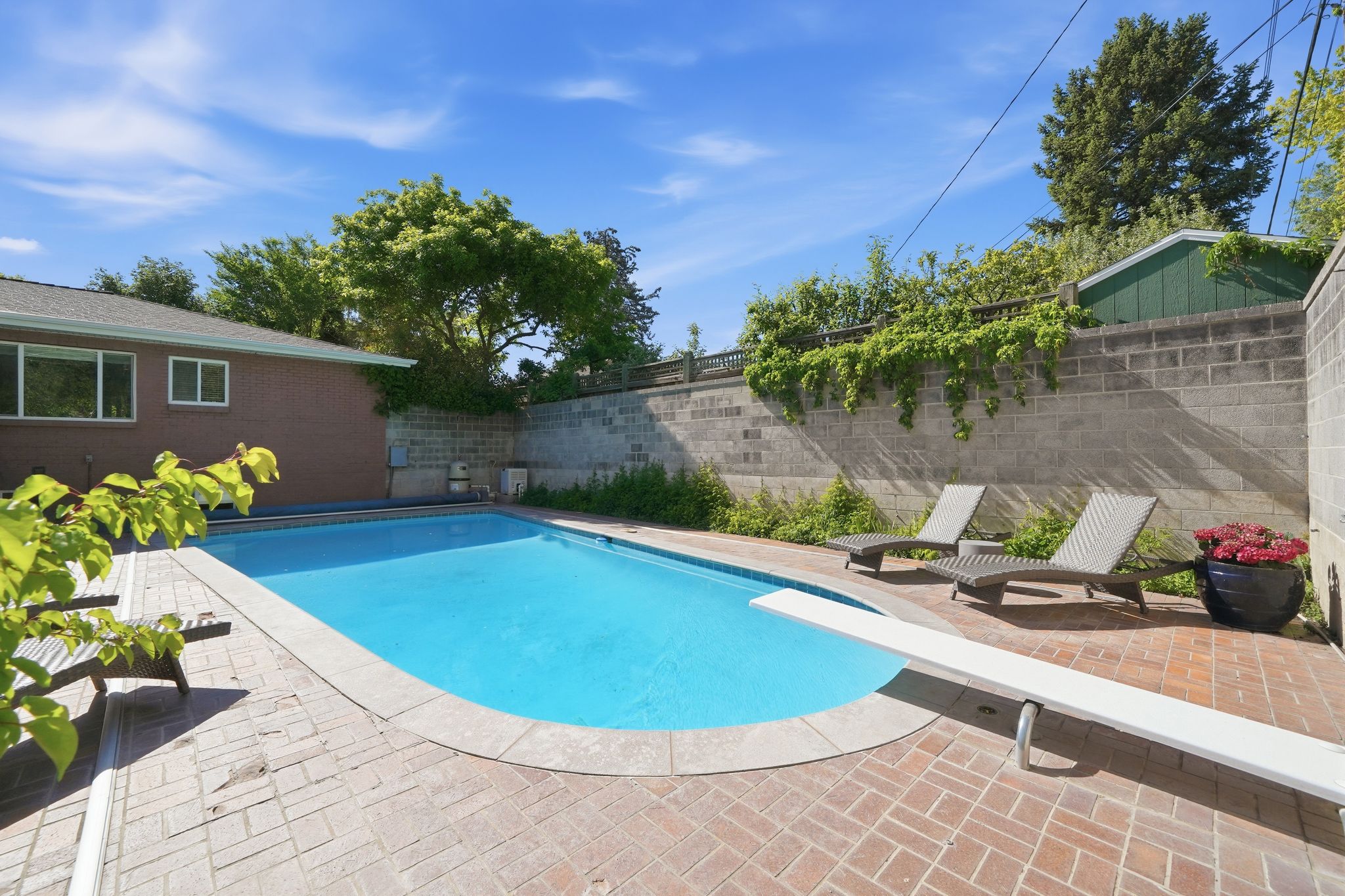 Expansive outdoor pool with a diving board, surrounded by brick paver decking