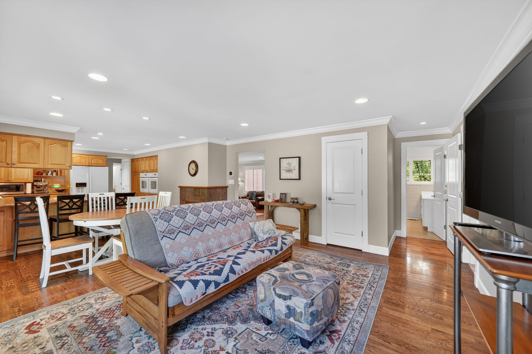 Open-concept living space featuring wood-finish flooring, recessed lighting, and crown molding
