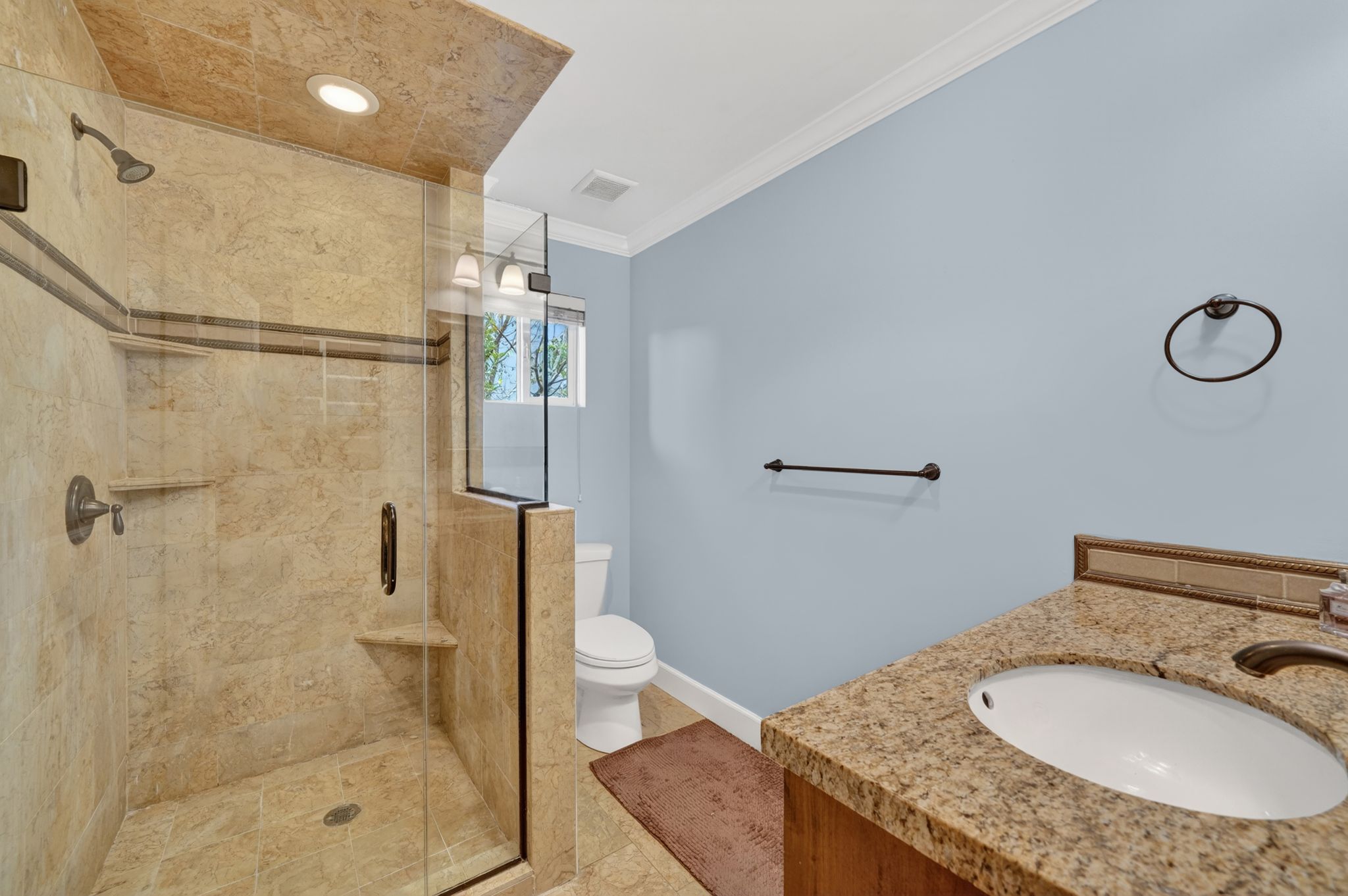 Spacious bathroom featuring a glass-enclosed shower with tile surround, built-in shelving, and bronze fixtures
