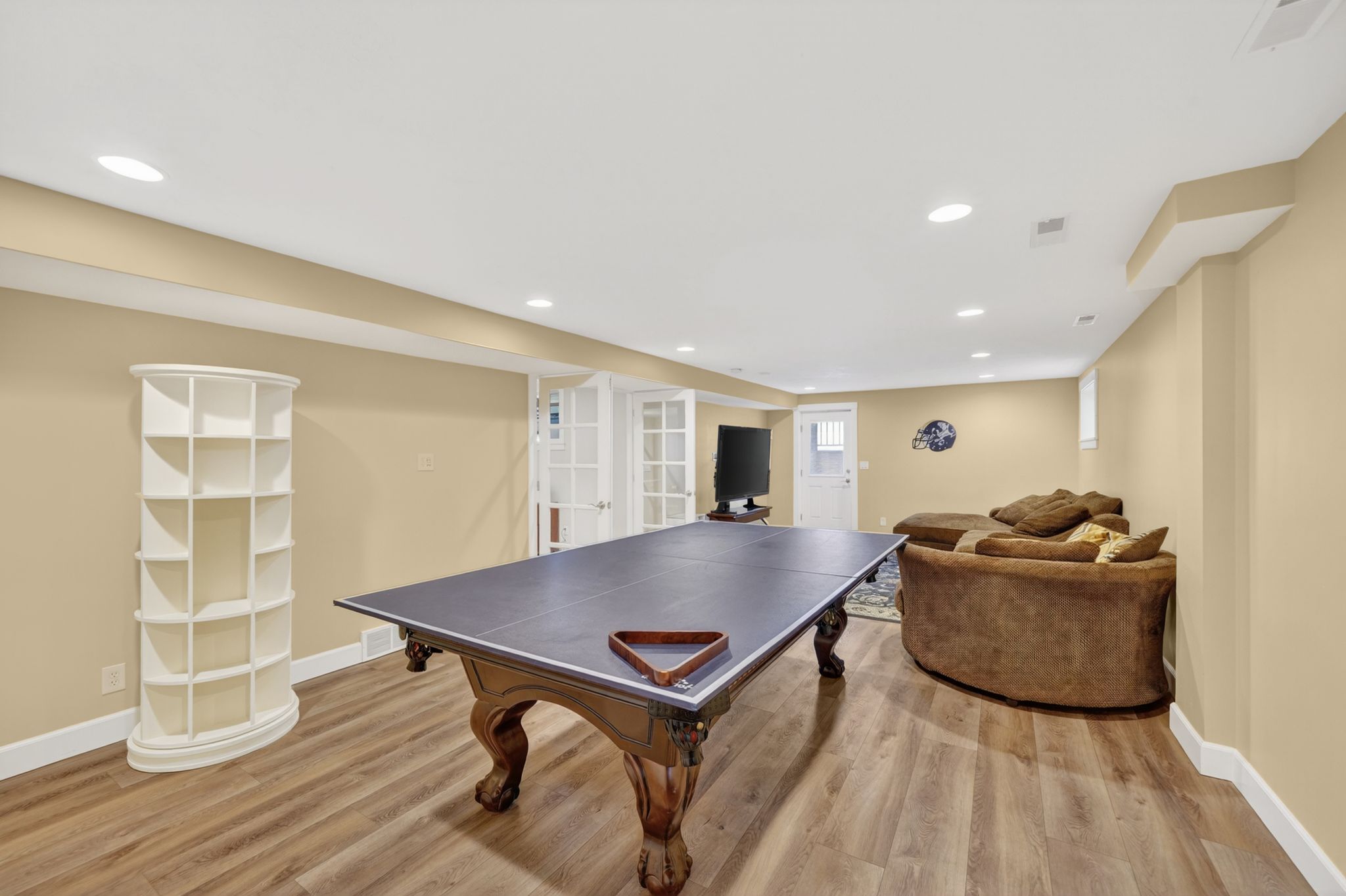 Spacious recreation area featuring wood-finish flooring, recessed lighting, and a neutral color palette