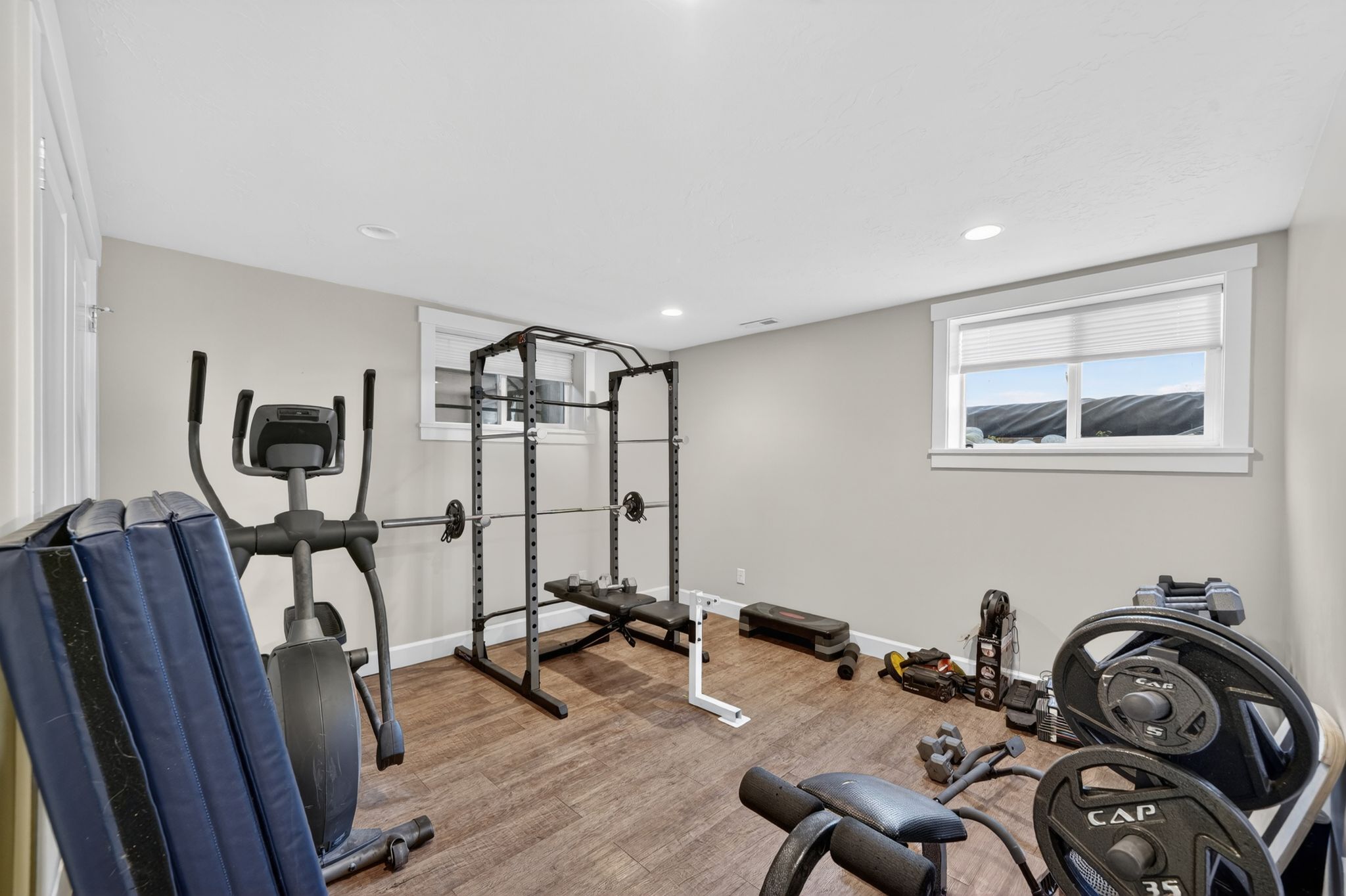 Spacious bonus room featuring wood-finish flooring, two windows with blinds, recessed lighting, and light grey wall paint