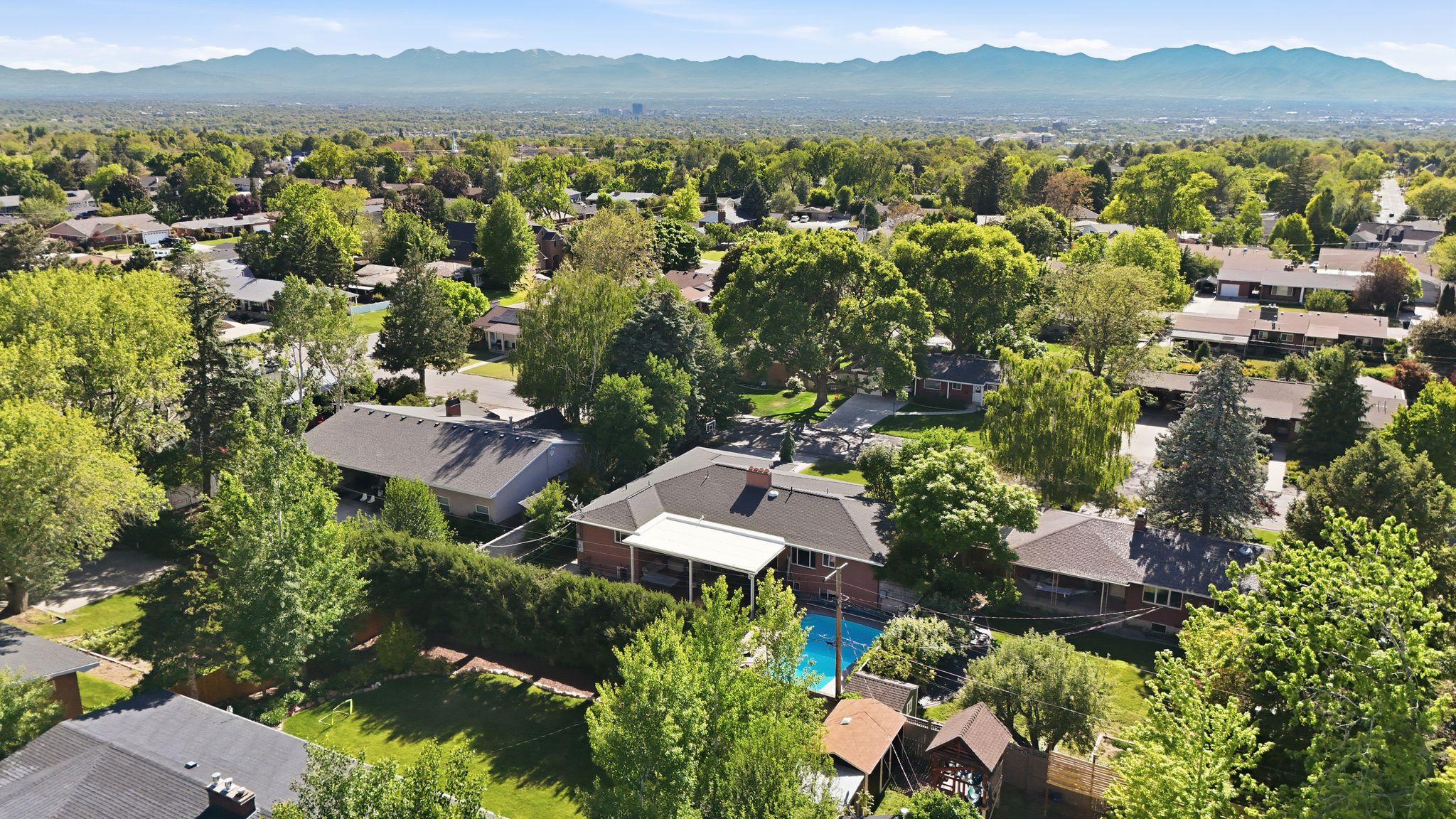 Expansive property featuring a swimming pool, mature trees, and a covered patio area