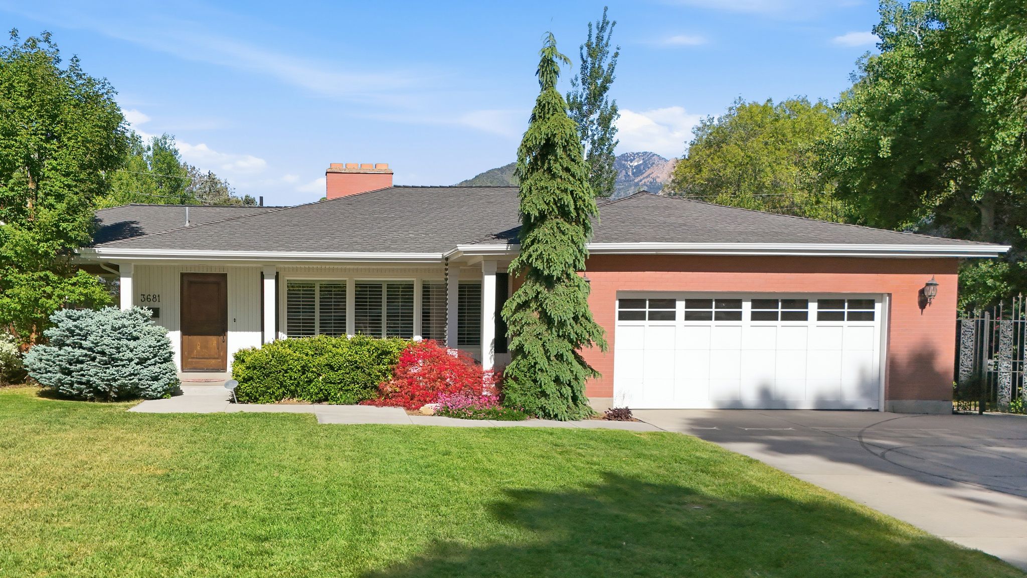 Ranch-style exterior with a dark shingle roof, white siding, and a red brick garage