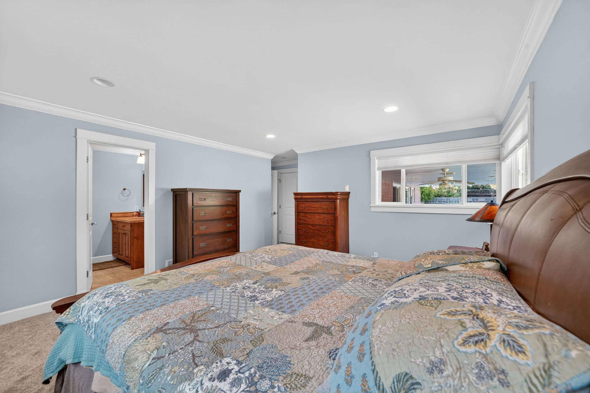 Carpeted bedroom featuring light blue walls, white trim, recessed lighting, and a window with white framing