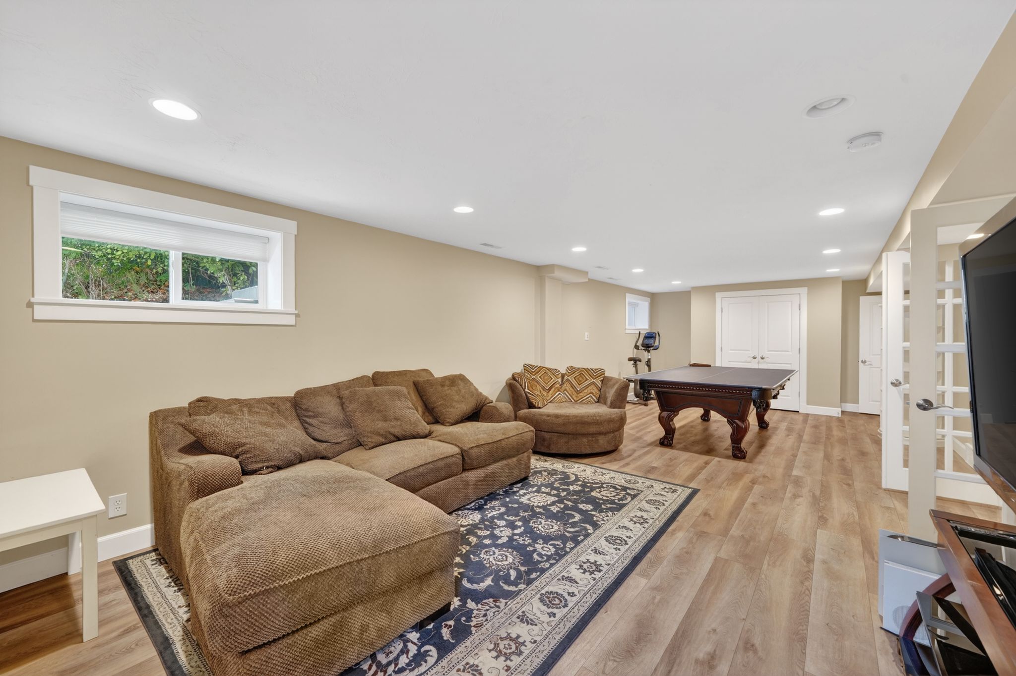 Spacious finished lower level with light wood-finish flooring, recessed lighting, and neutral wall tones