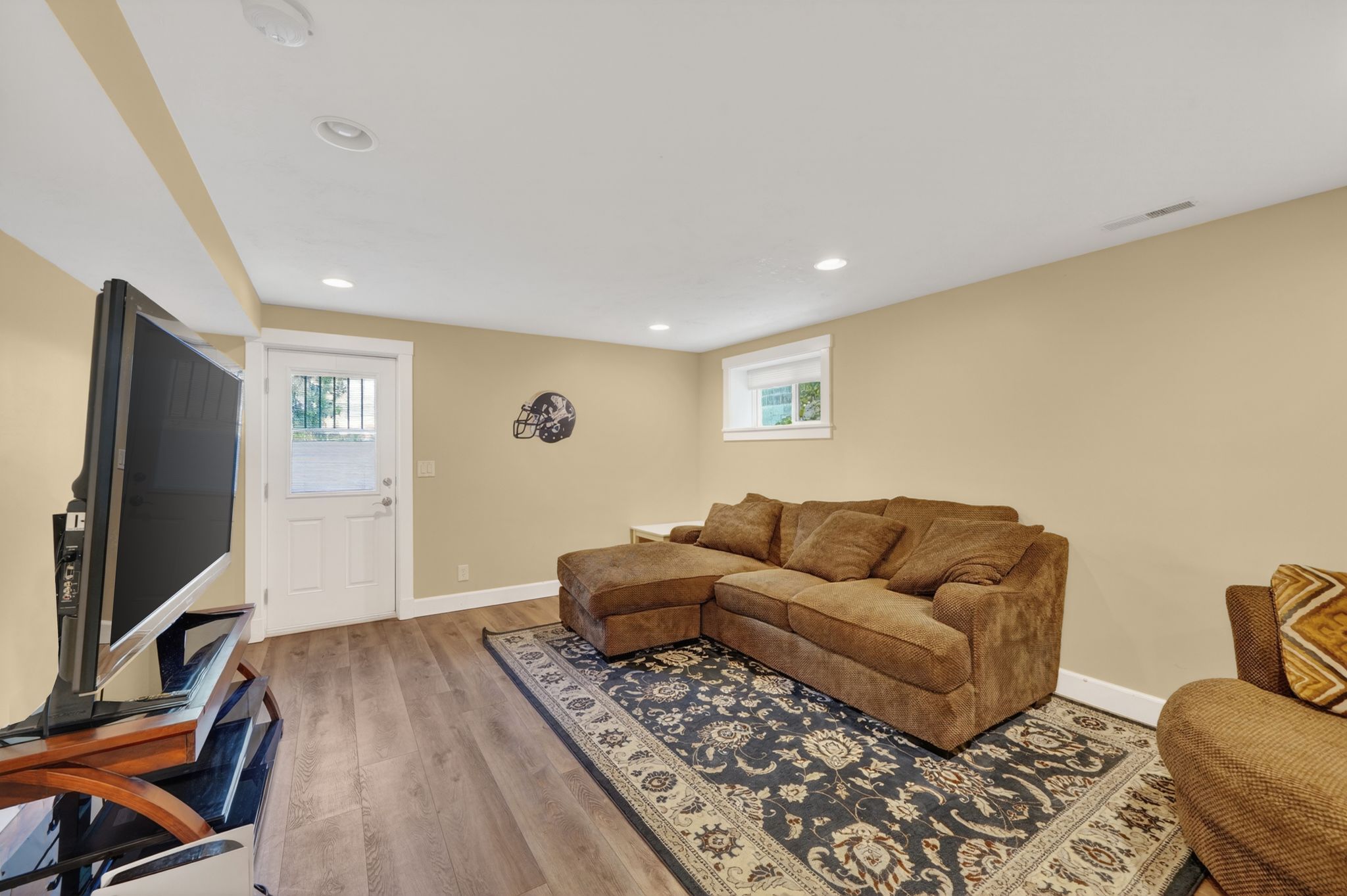 Finished room featuring wood-finish flooring, recessed lighting, and a white paneled exterior door with a glass insert