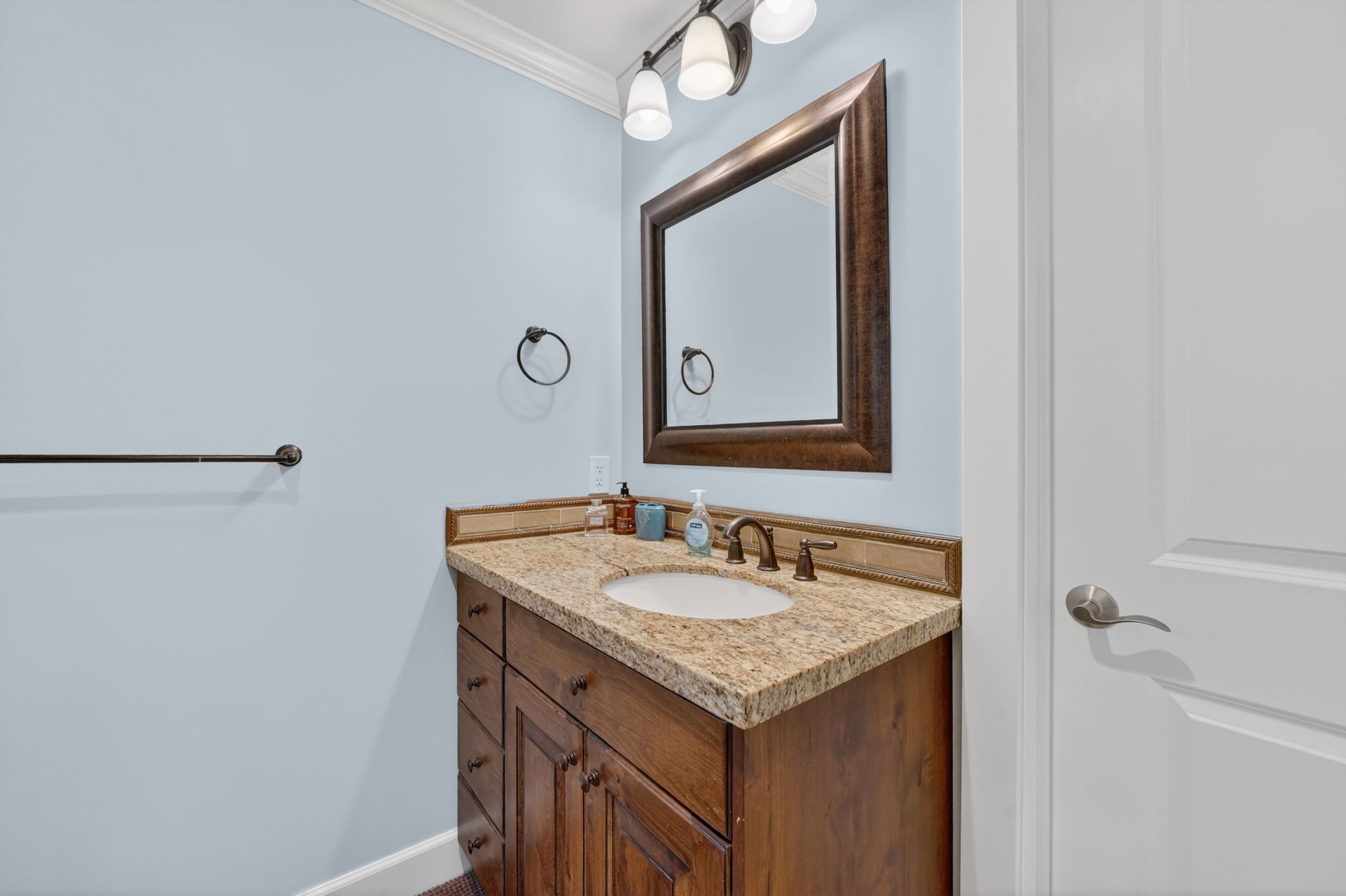 Wood-finish vanity with an undermount sink, granite countertop, and oil-rubbed bronze fixtures