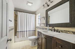 Bathroom featuring a dark wood-finish vanity with an integrated sink, a dark framed mirror, and a tile shower surround