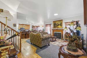 Spacious living area featuring a fireplace with a wood mantle and hearth, recessed lighting, and a wood-finish staircase with balusters