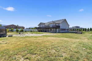 Rear exterior featuring a multi-level deck, lower level patio, and a spacious grassy area