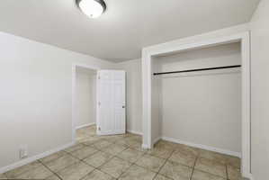 Room featuring light-colored tile flooring, white baseboards, and a white six-panel door