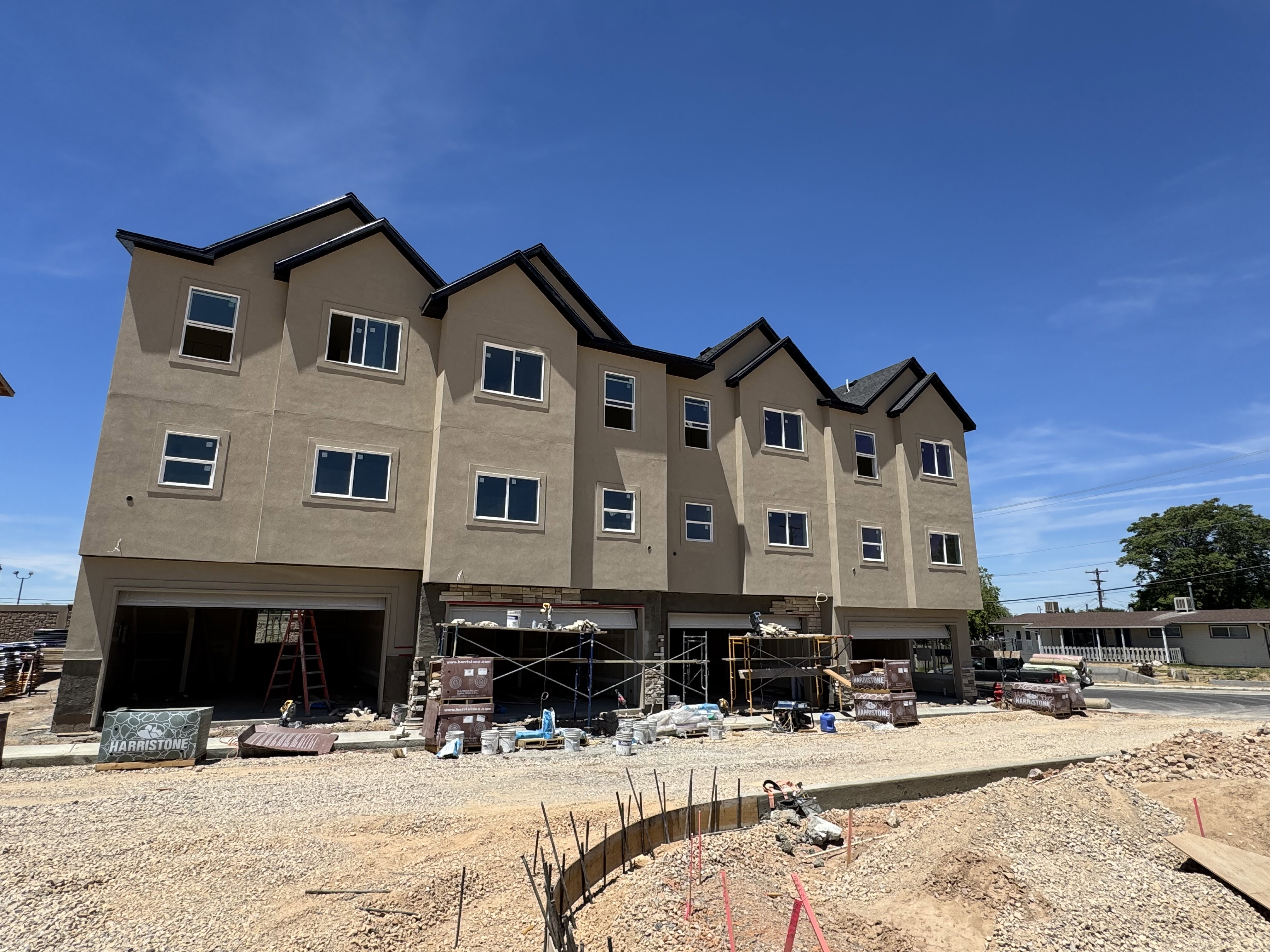 Multi-story building featuring tan stucco siding and dark-trimmed gable roofs