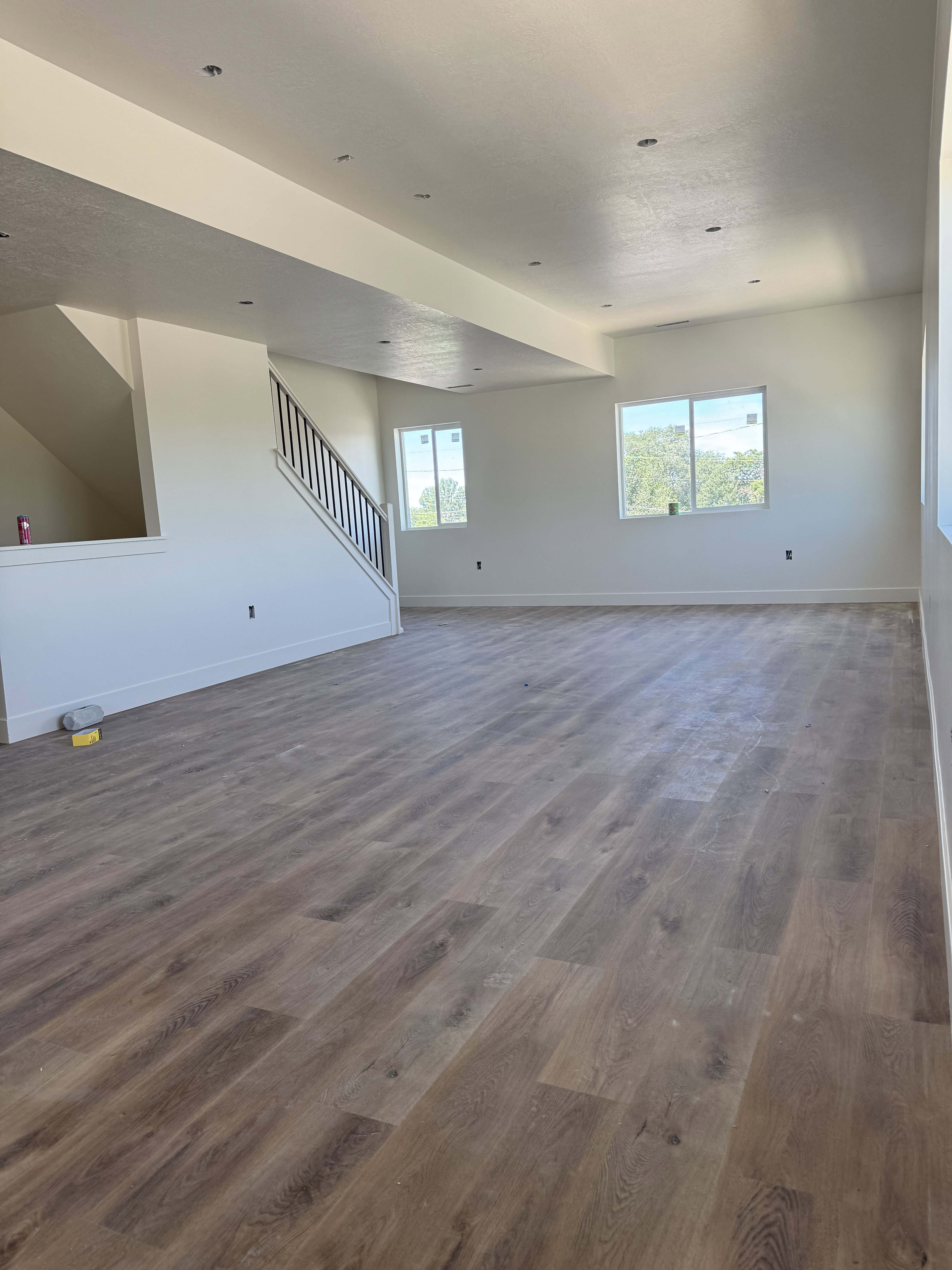 Spacious room featuring wood-finish flooring, recessed ceiling lighting, and multiple windows providing natural light
