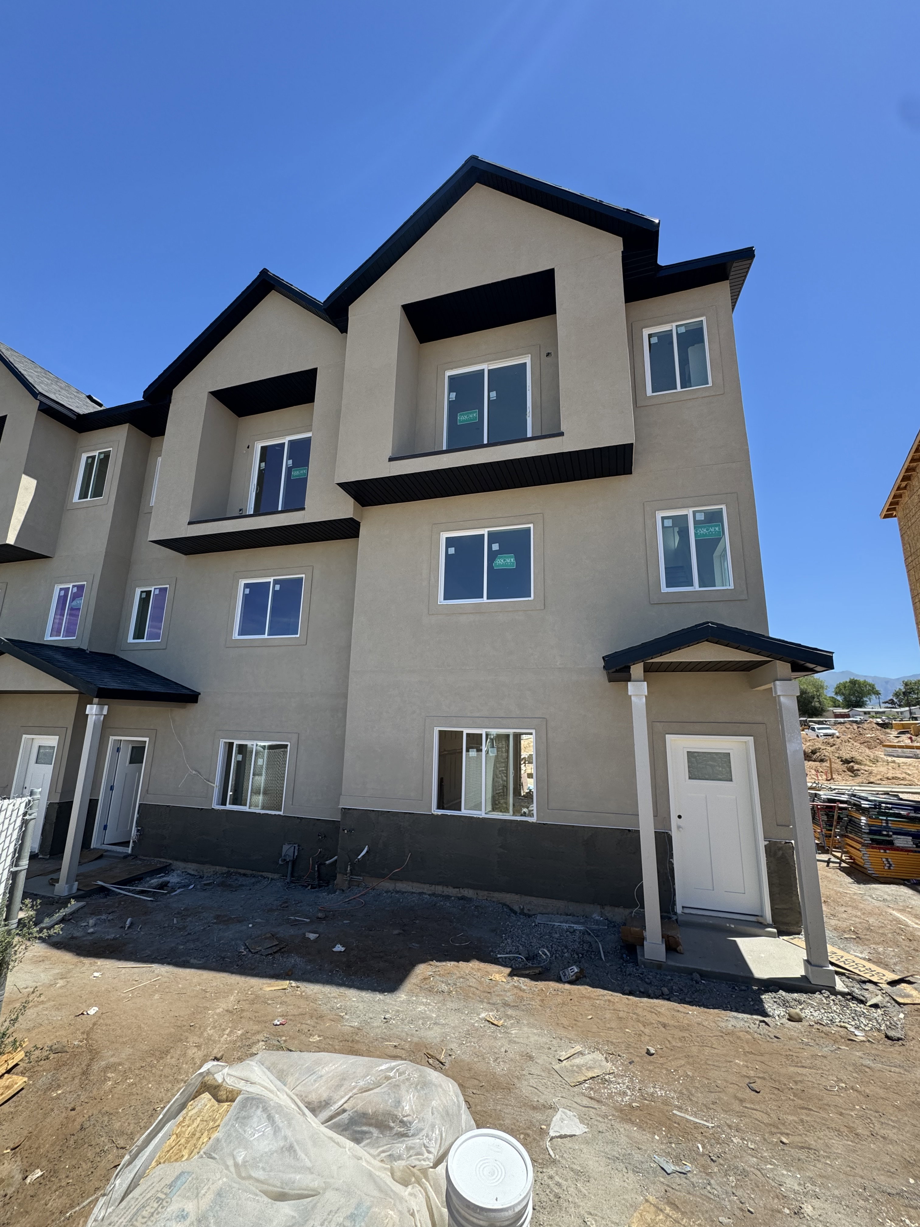 Contemporary multi-story facade featuring stucco siding, multiple windows, and a covered entry