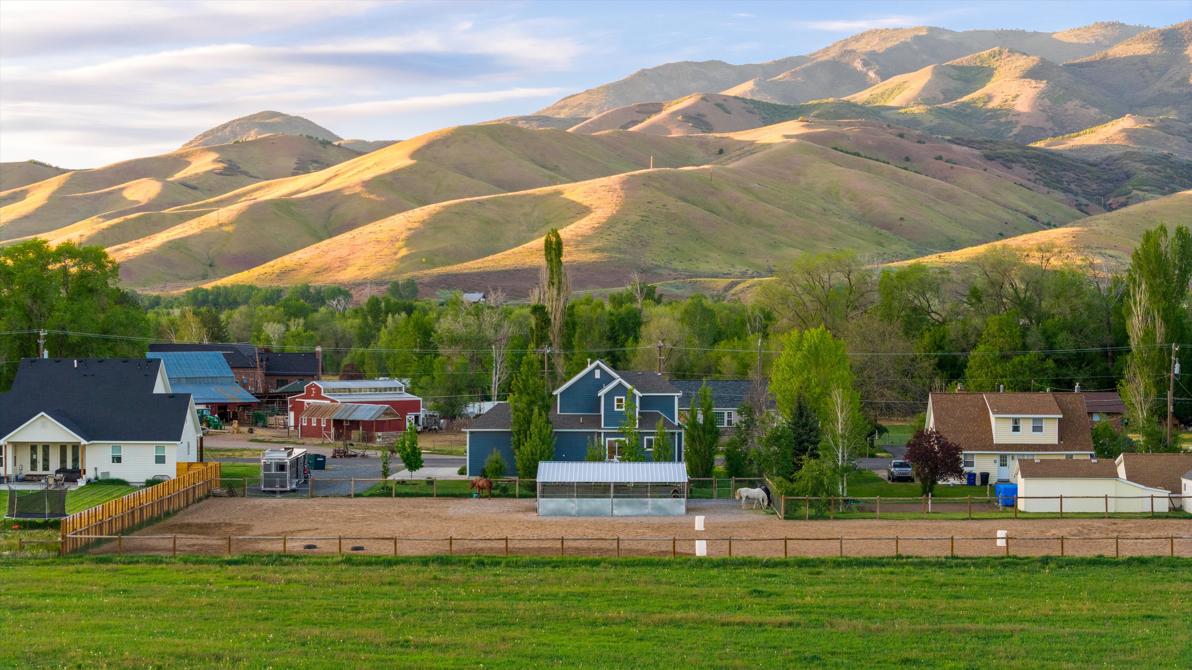 Expansive property featuring a large equestrian riding arena, white fencing, and a variety of mature trees