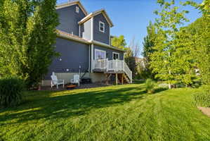 Expansive green lawn surrounds the property, featuring mature trees and landscaping