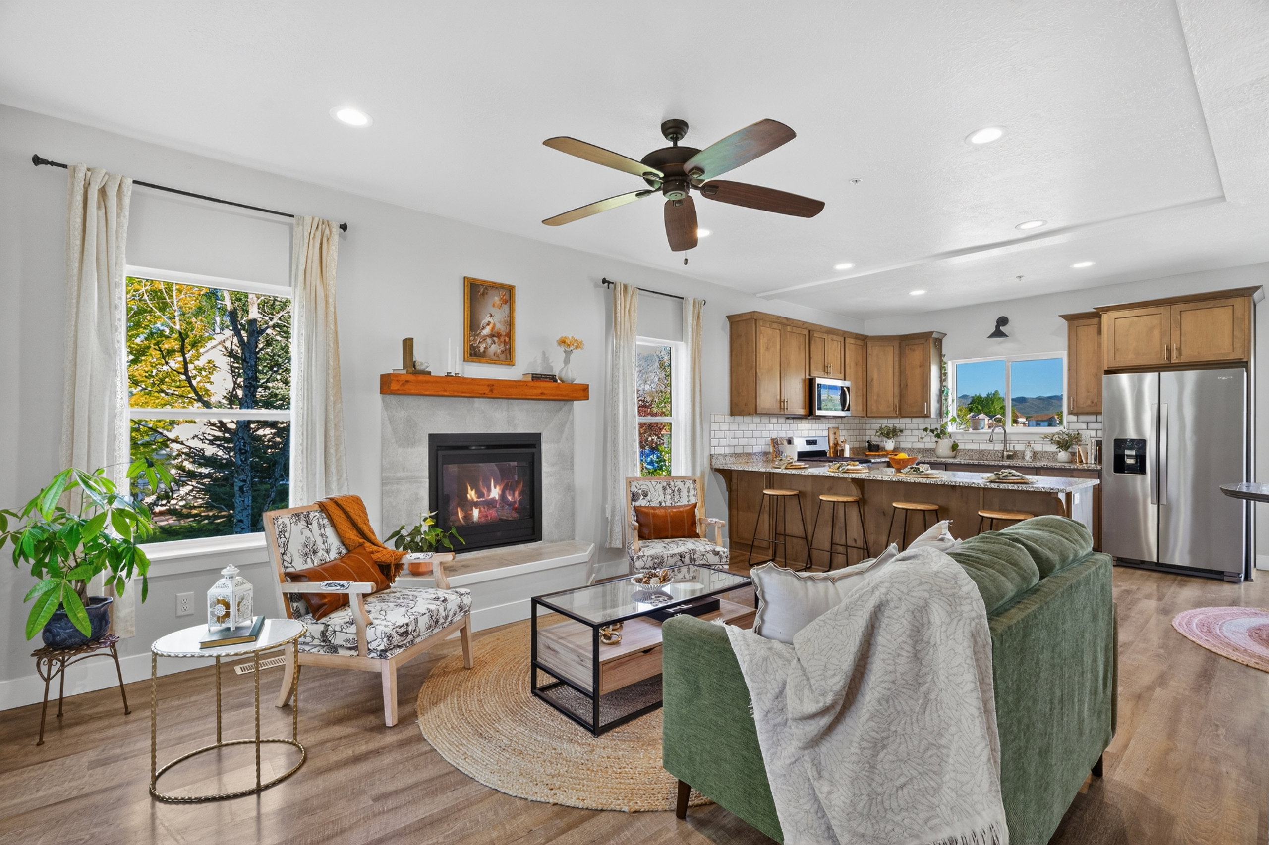 Open concept living area featuring wood-finish flooring, a contemporary fireplace with a wood mantle, and recessed lighting