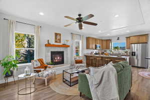 Open concept living area featuring wood-finish flooring, a contemporary fireplace with a wood mantle, and recessed lighting