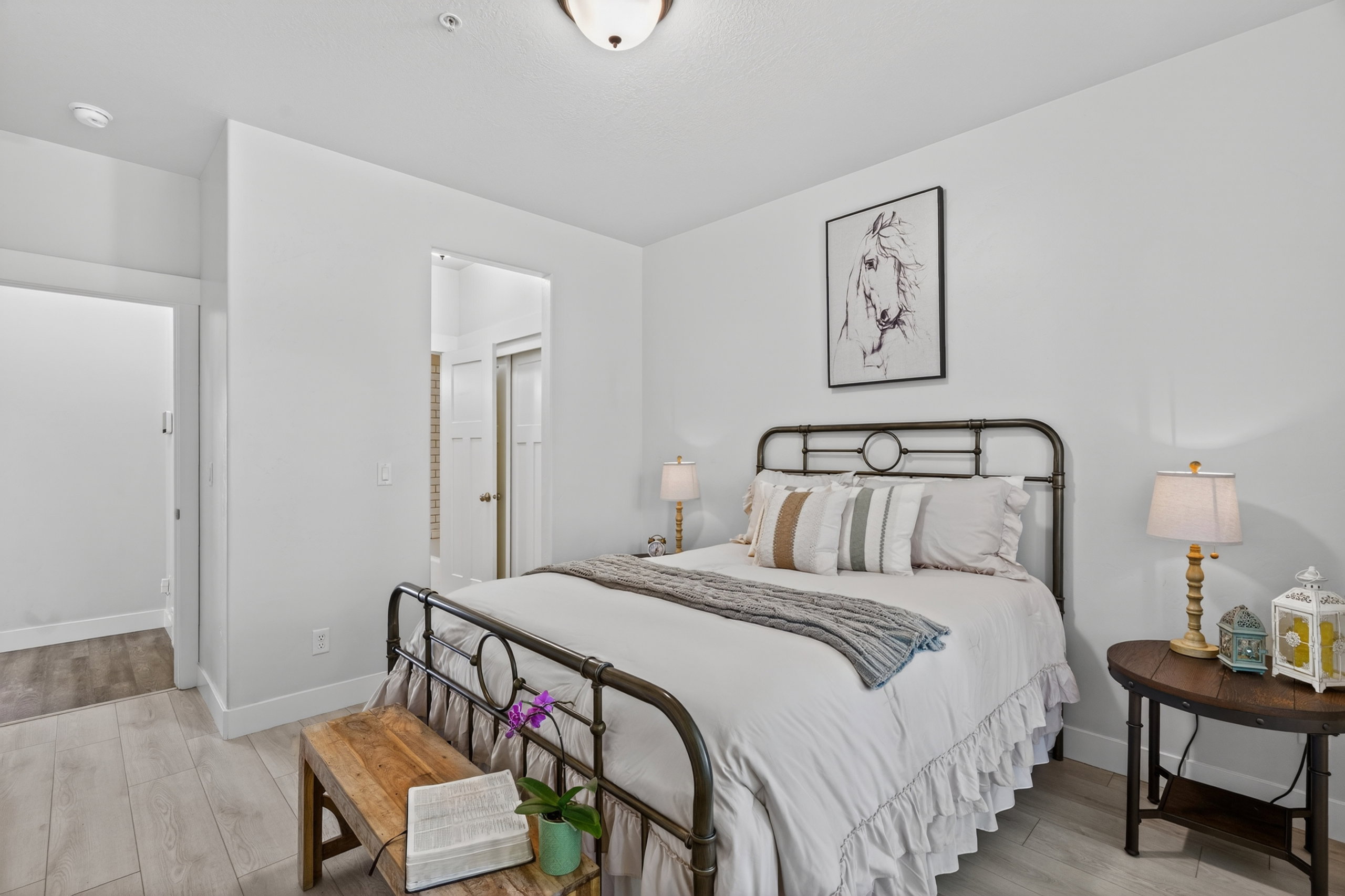 Spacious room featuring light wood-finish flooring, crisp white walls, a doorway to an additional space, and a ceiling-mounted light fixture