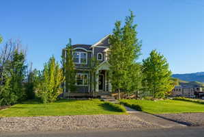Two-story residence featuring gray siding, white trim, and a prominent arched window dormer