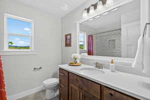 Bathroom featuring a single window, a dark wood-finish vanity with a light countertop, a built-in sink, and a large mirror with overhead lighting