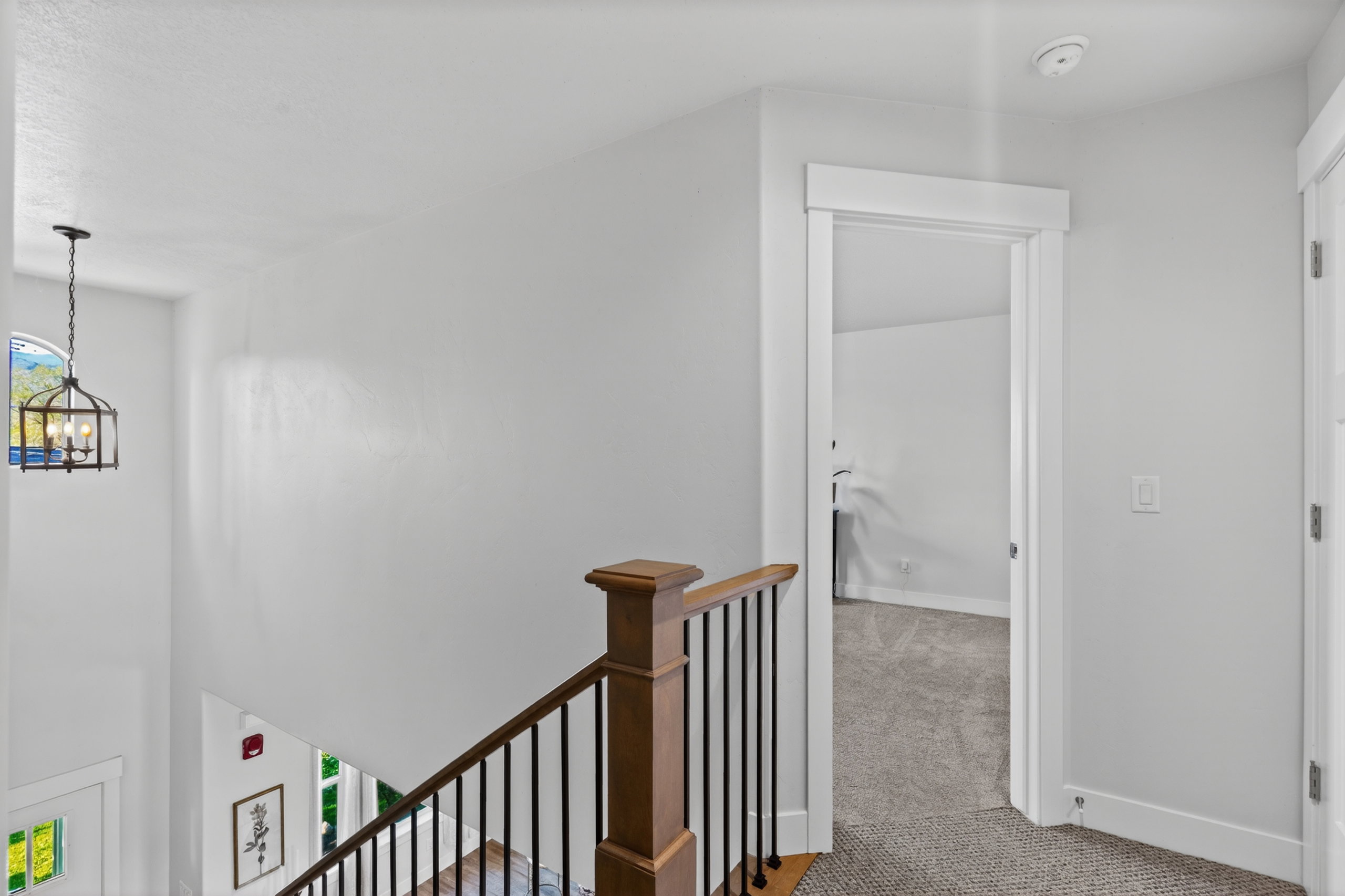 Staircase featuring wood-finish handrail, black balusters, and white risers