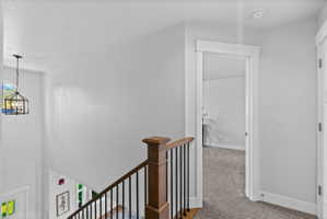 Staircase featuring wood-finish handrail, black balusters, and white risers