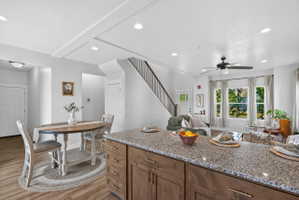 Kitchen island featuring a granite-style countertop and wood-finish cabinetry with brass hardware