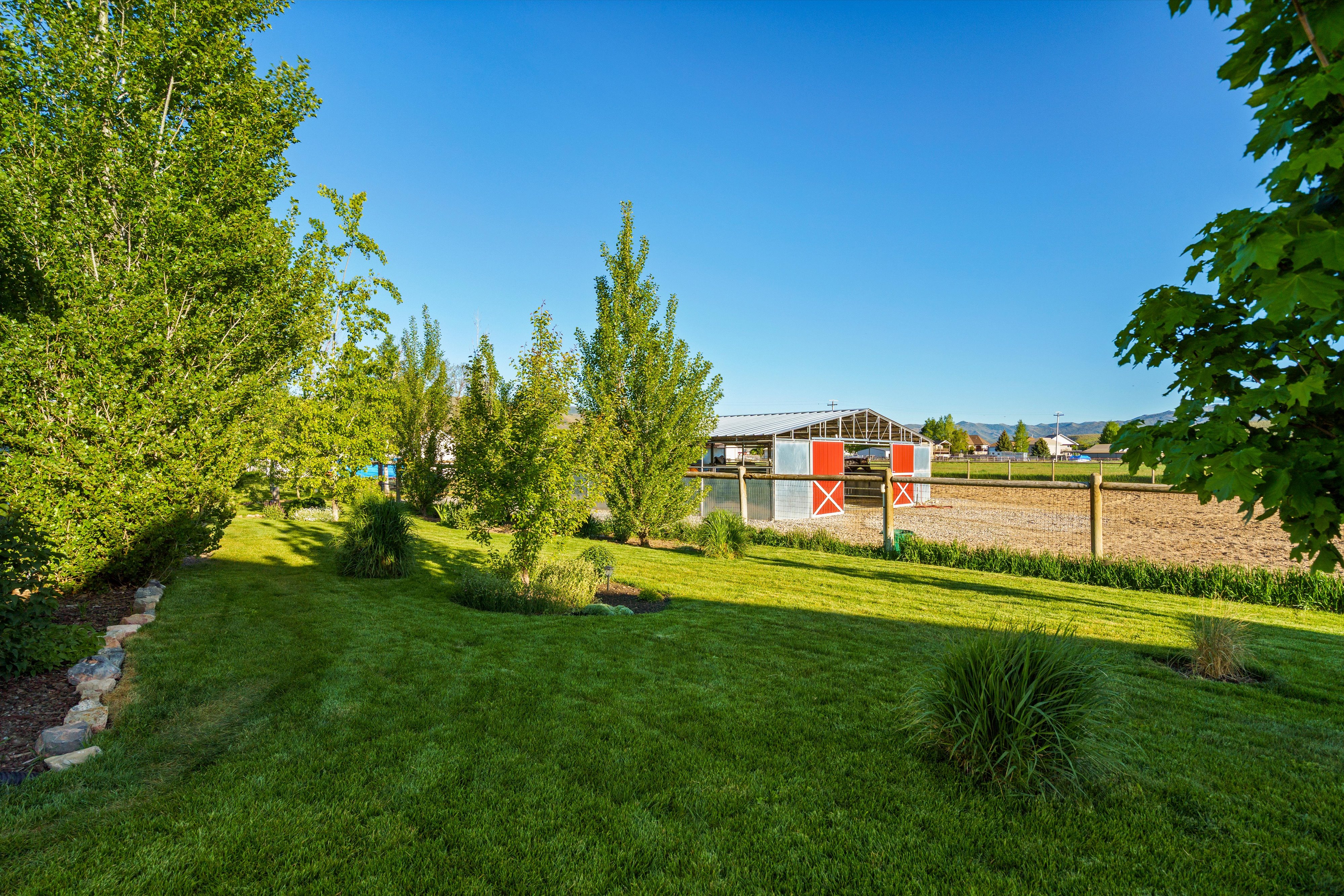 Expansive backyard featuring a manicured lawn, established trees, and natural stone landscaping