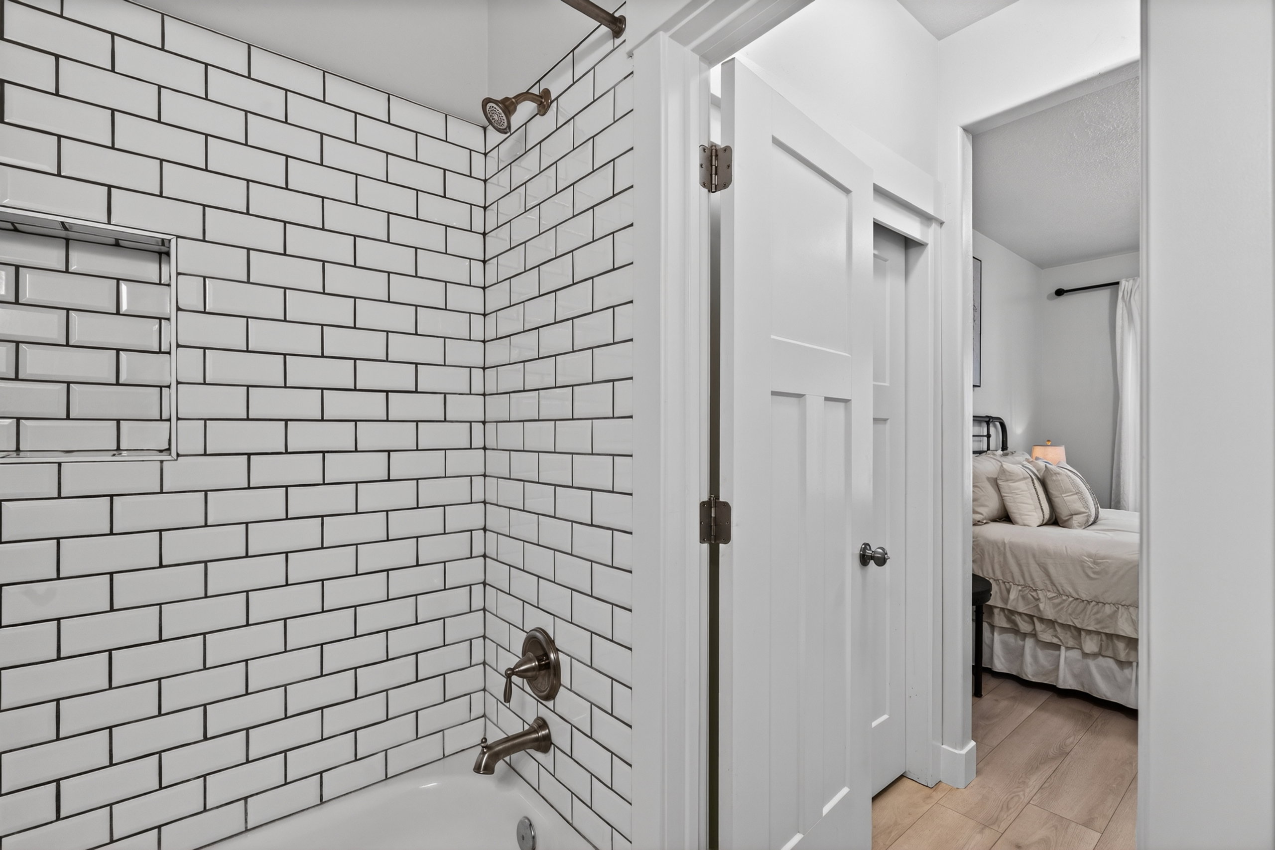 White subway tile shower surround with a built-in niche and bronze-finish fixtures