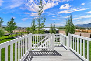 Composite deck with white railings and gate overlooking horse barn and pasture.
