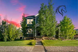 Two-story residence featuring a dark siding exterior, white trim, and a covered front porch