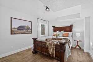 Bedroom featuring wood-finish flooring, white baseboards, and light-colored walls