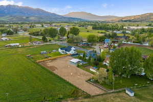 Expansive property featuring a large equestrian arena, white-sided main residence with a dark roof, and a covered structure