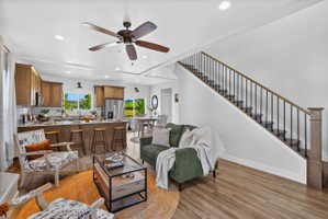 Open-concept living area featuring wood-finish flooring and a staircase with dark metal balusters