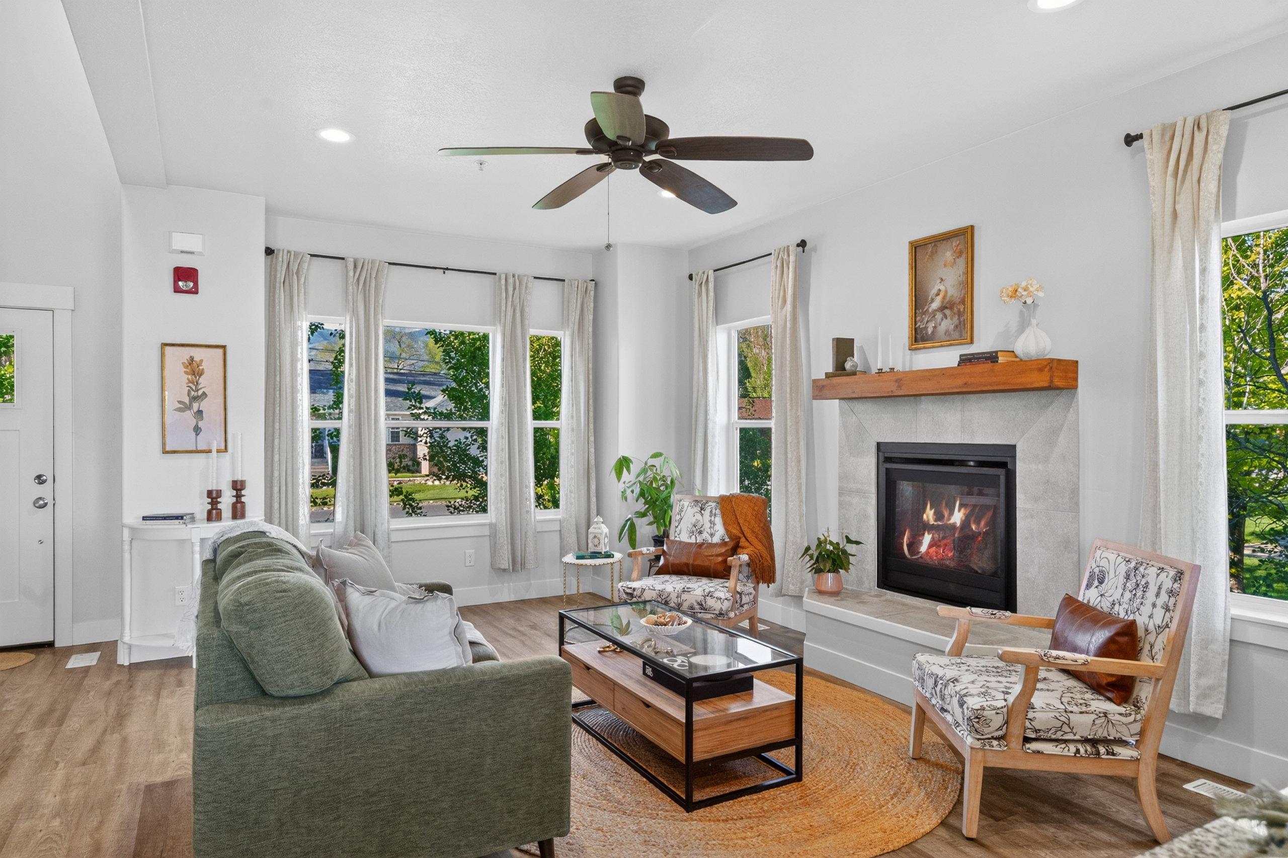 Living area featuring a modern fireplace with a substantial wood mantel, surrounded by multiple windows