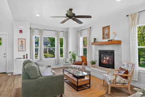 Living area featuring a modern fireplace with a substantial wood mantel, surrounded by multiple windows