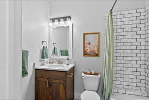 Bathroom featuring a white subway tile shower, wood-finish vanity with countertop, and framed mirror with integrated lighting