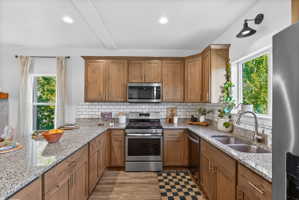 U-shaped kitchen featuring wood cabinetry, stainless steel appliances, granite countertops, and a subway tile backsplash