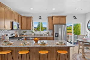 Kitchen featuring granite countertops, wood cabinetry, stainless steel appliances, and a subway tile backsplash