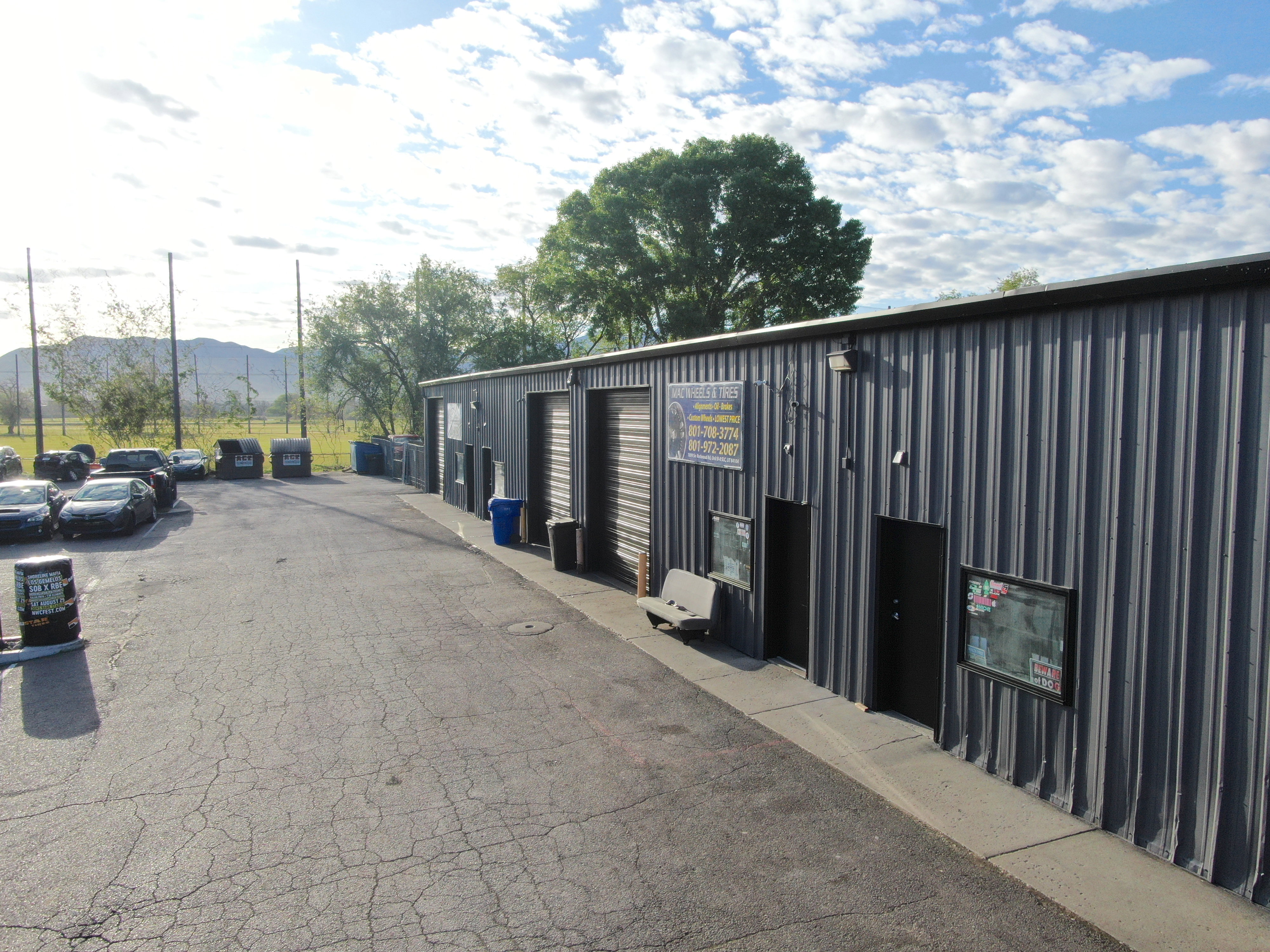 Industrial building featuring corrugated metal siding, multiple roll-up doors, and a paved parking area