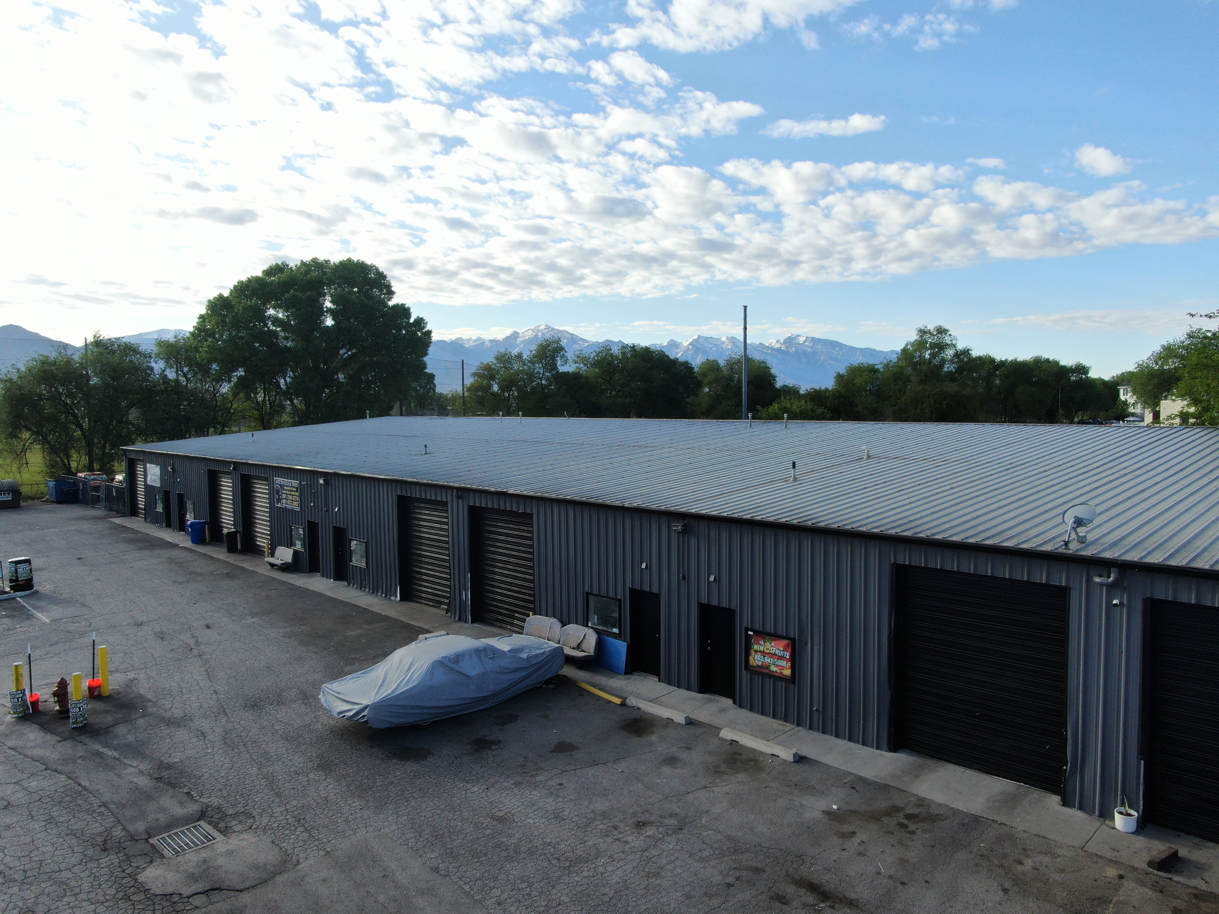 Commercial building with multiple roll-up garage doors, corrugated metal siding, and a standing seam metal roof