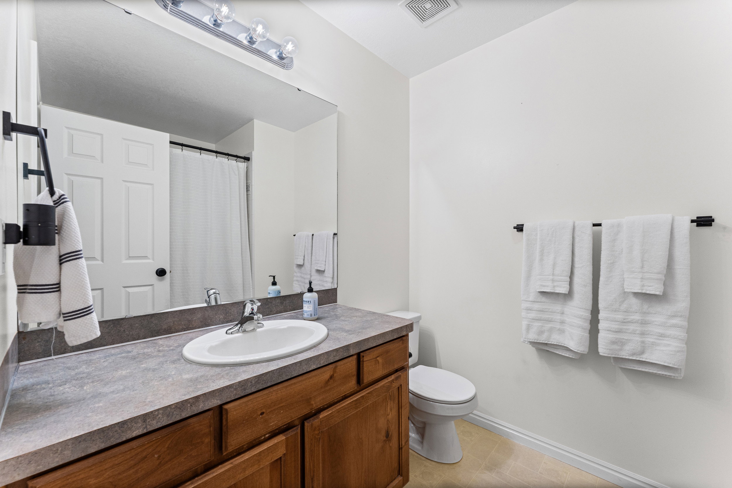 Bathroom featuring a wood-finish vanity with an oval sink and a spacious countertop
